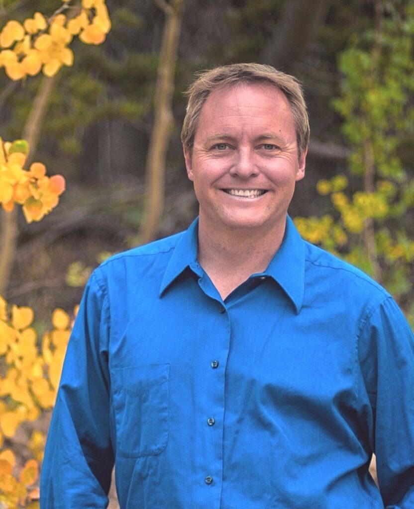 Larsen Picture of Kristopher Larsen wearing a blue shirt against a backdrop of yellow aspens.